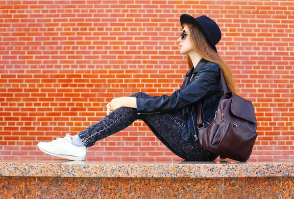Мода красива жінка в чорному рок-стилі сидить над цеглою спиною — стокове фото