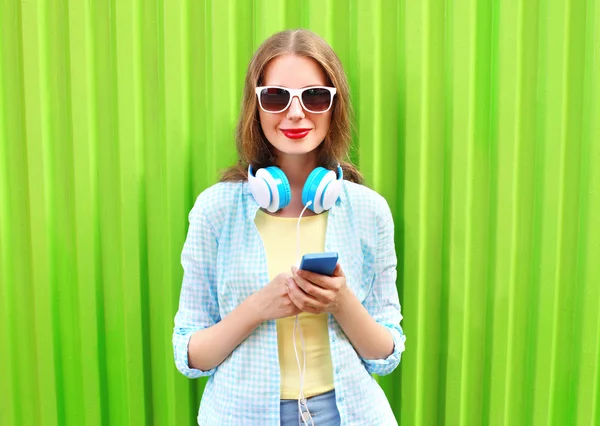 Hermosa mujer escucha música en los auriculares con teléfono inteligente — Foto de Stock