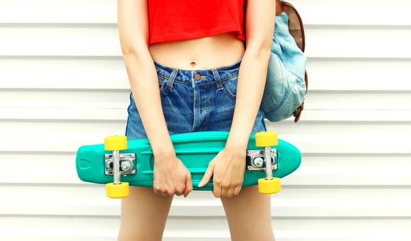 Menina da moda com skate em shorts sobre fundo branco — Fotografia de Stock