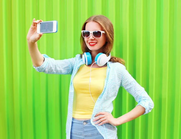 Прелестная крутая девушка делает автопортрет на смартфоне через зеленый — стоковое фото