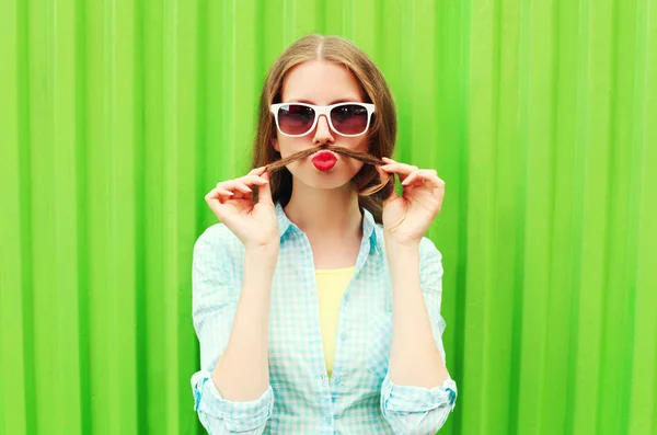 Mujer divirtiéndose muestra bigote pelo sobre fondo verde — Foto de Stock