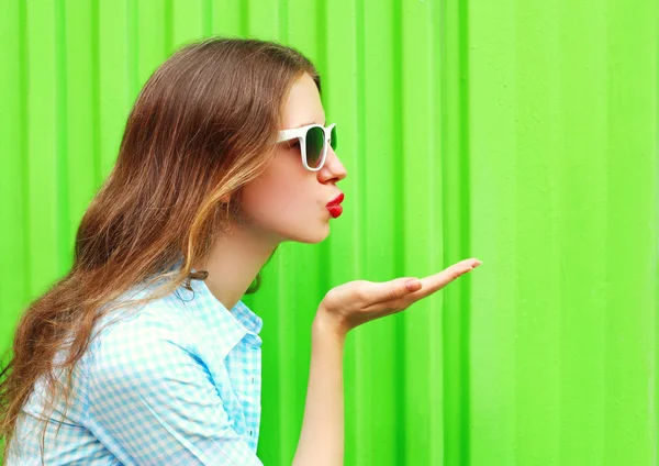 Frau mit Sonnenbrille schickt Luftkuss über buntes grünes Backgr — Stockfoto