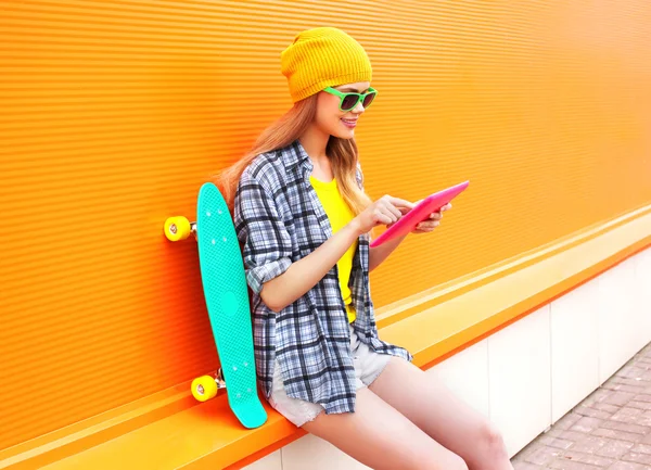 Leuk meisje mode met behulp van tablet pc met skateboard over co — Stockfoto