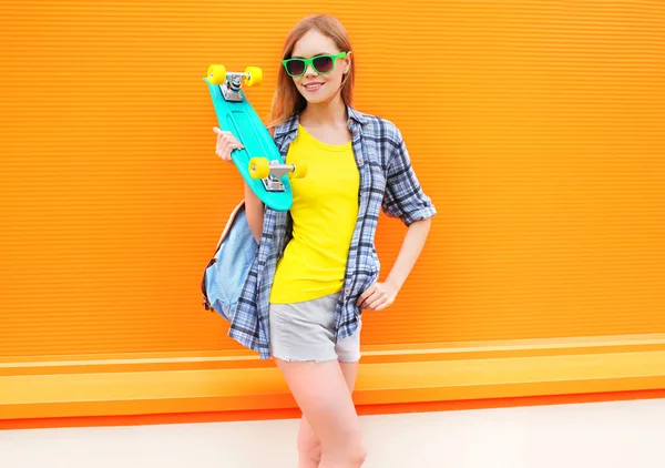 Mode vrij lachende meisje met skateboard over kleurrijke oranje — Stockfoto