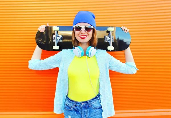 Модная симпатичная девушка со скейтбордом в городе за окном — стоковое фото