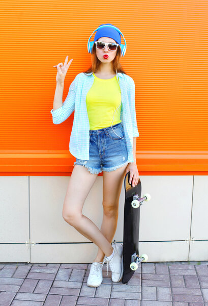 Fashion pretty cool girl with skateboard listens to music over c