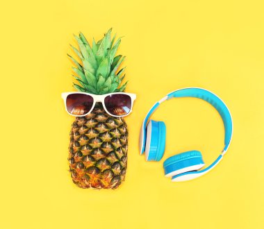 Renkli y üzerinde güneş gözlüğü ve kulaklık ile Moda ananas