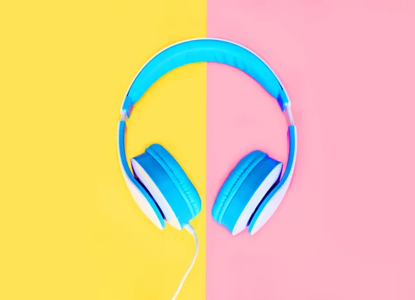 Blue headphones over colorful yellow pink background top view — Stock Photo, Image