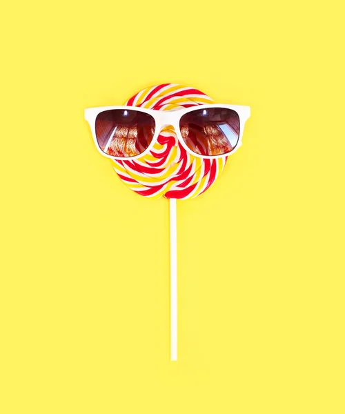 Colorido caramelo lollipop en palo con gafas de sol sobre amarillo b — Foto de Stock