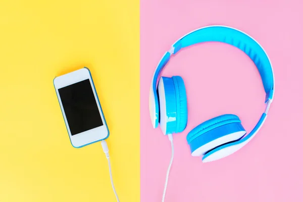 Headphones connected to white smartphone over colorful yellow pi — Stock Photo, Image