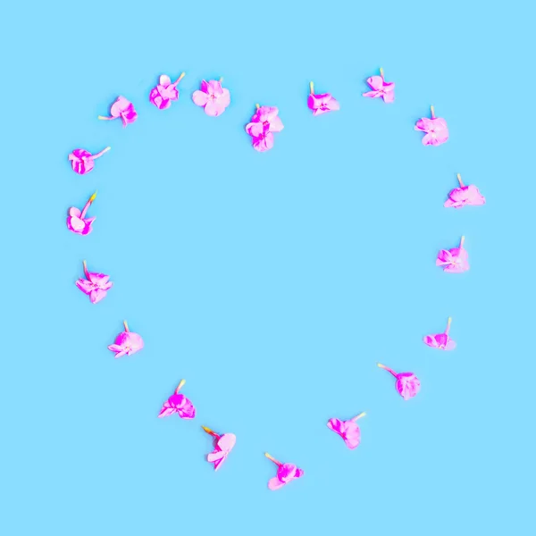 Coeur en forme de pétales fleurs sur fond bleu coloré — Photo