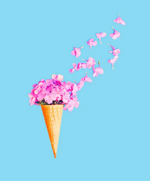Cône de crème glacée avec pétales fleurs sur fond bleu vue de dessus — Photo