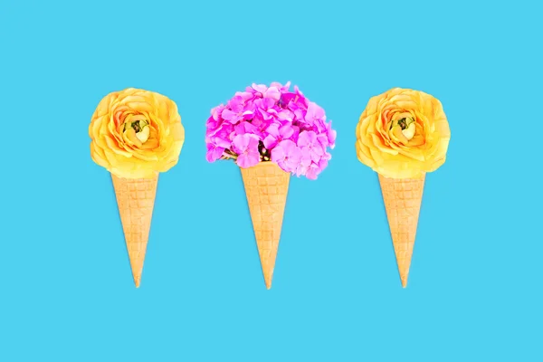Trois cône de crème glacée avec des fleurs sur fond bleu coloré — Photo