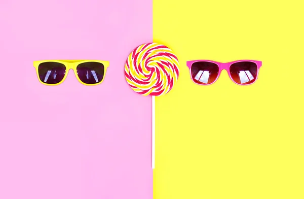 Two sunglasses and colorful lollipop caramel on stick over pink — Stock Photo, Image