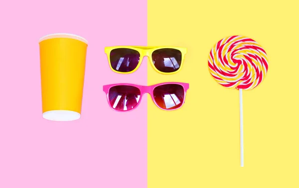 Dos gafas de sol y colorido caramelo piruleta en palo con la taza j — Foto de Stock