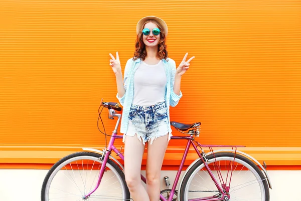 Mode hübsche lächelnde Frau mit Fahrrad über bunte orange b — Stockfoto