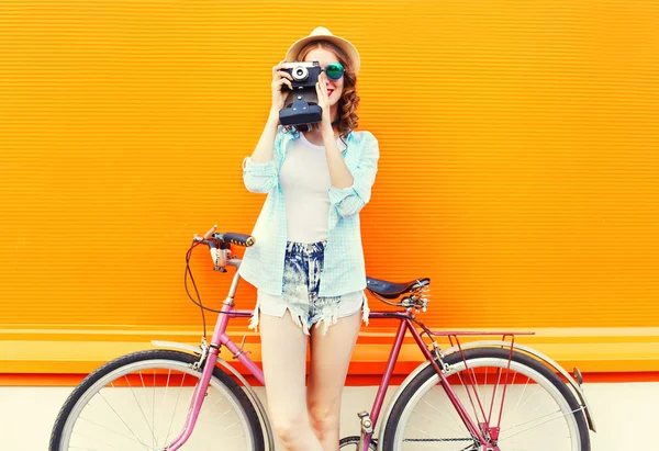 Mode hübsche Frau mit Retro-Kamera und Fahrrad über bunte — Stockfoto