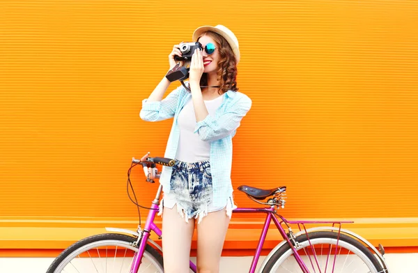 Mode hübsche Frau mit Retro-Kamera und Fahrrad über bunte — Stockfoto