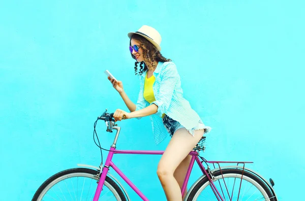 Całkiem fajna uśmiechnięta kobieta za pomocą smartfona na rowerze retro nad — Zdjęcie stockowe