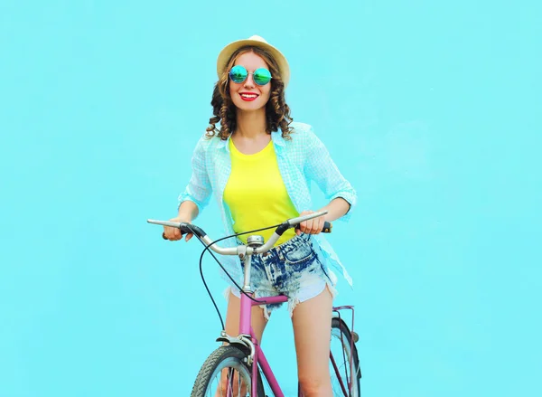 Mulher muito sorridente monta uma bicicleta sobre backgrou azul colorido — Fotografia de Stock