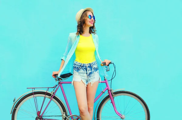 Hübsche lächelnde Frau mit Fahrrad vor buntem blauen Hintergrund — Stockfoto