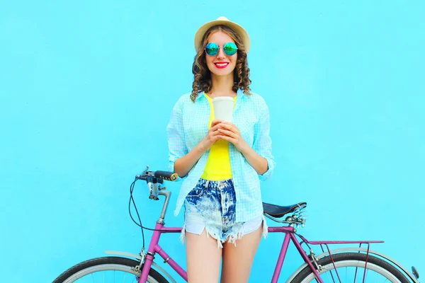 Hübsche lächelnde Frau mit Kaffeetasse und Fahrrad über buntem b — Stockfoto