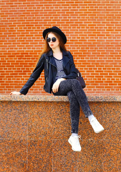 Fashion young woman wearing a black rock style sitting over bric — Stock Photo, Image