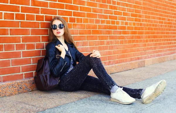 Moda mujer joven en estilo rock negro sentado sobre la pared de ladrillos —  Fotos de Stock