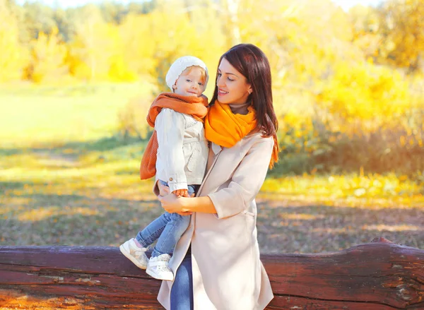 Szczęśliwy uśmiechający się matka trzyma na rękach dziecko w jesienny dzień — Zdjęcie stockowe