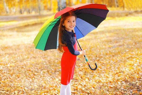 Gelukkig klein meisje kind met kleurrijke paraplu in zonnige herfst d — Stockfoto