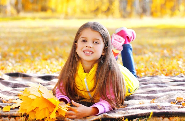 Retrato niño sonriente con hojas de arce amarillo acostado en el plai —  Fotos de Stock