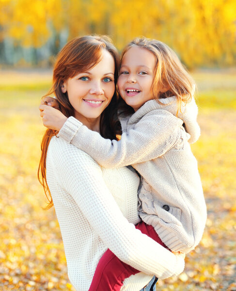 Portrait happy smiling mother hugging child in warm sunny autumn