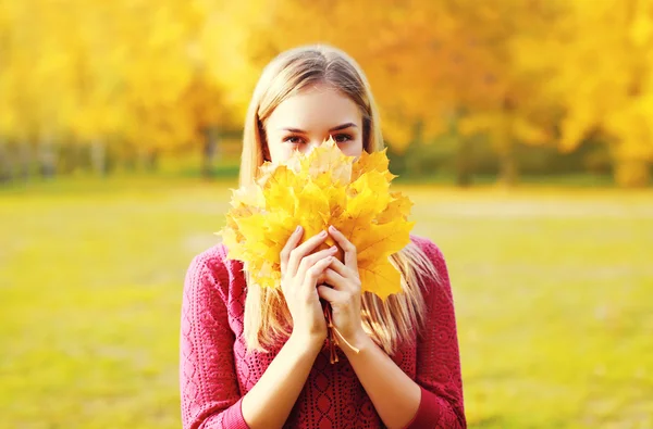 美丽微笑的女人隐藏她的脸黄色枫叶 lea 的肖像 — 图库照片