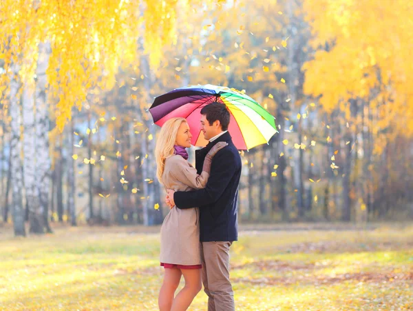 Glückliches Liebespaar mit buntem Regenschirm im warmen, sonnigen Tag — Stockfoto