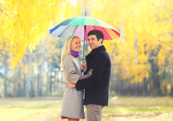 Feliz casal sorridente amoroso com guarda-chuva colorido em quente ensolarado — Fotografia de Stock