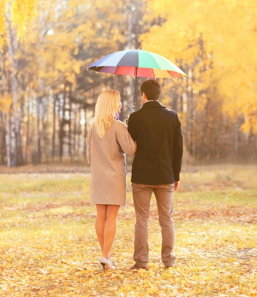 Jeune couple avec parapluie coloré dans autum chaud et ensoleillé — Photo