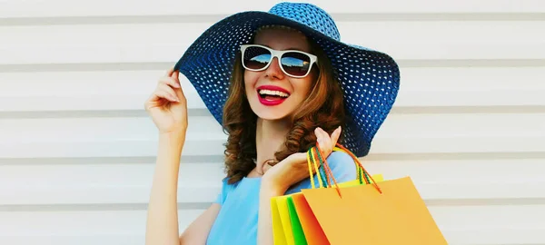 白い背景に青いドレス 夏のわらの帽子を身に着けているショッピングバッグと笑顔の若い女性を閉じ肖像画 — ストック写真