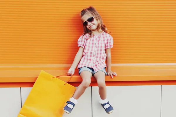 Dziewczynka Dziecko Torbami Zakupy Ulicy Miasta Pomarańczowym Tle — Zdjęcie stockowe