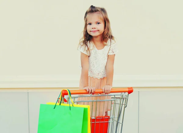 Menina Feliz Criança Sentada Carrinho Carrinho Com Sacos Compras Sobre — Fotografia de Stock