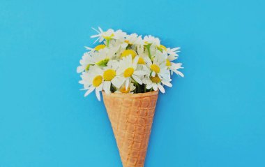 Mavi arka planda pembe çiçekli dondurma külahı