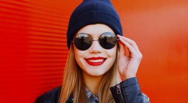 Kırmızı arka planda siyah rock tarzında gülümseyen güzel bir kadının portresi.