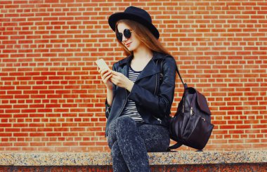 Duvarın arkasında telefonu olan genç bir kadının portresi.