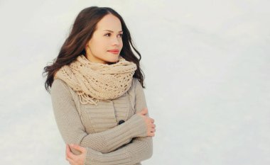 Dışarıda örgü örmüş, süveter giyen güzel esmer bir kadının portresi.