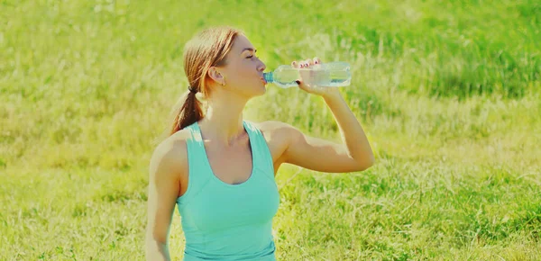 健康的女人夏天在草地上用瓶子喝水 — 图库照片