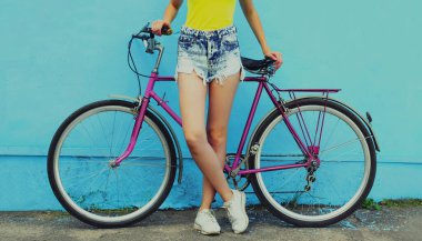 Mavi arka planda bisiklet pozu veren şortlu güzel kadın modelini kapat.