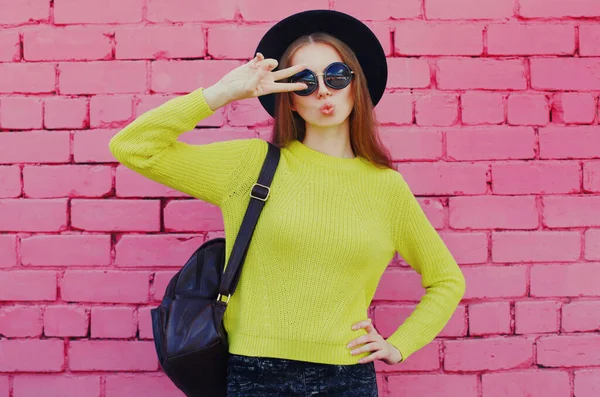 ピンクのレンガの壁の背景に黄色のニットセーターを身に着けているスタイリッシュな若い女性の肖像画 — ストック写真