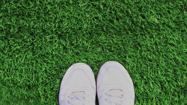 Close up white sports sneakers on a green grass background, blank copy space
