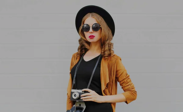 灰色の背景にBohoスタイルを身に着けているヴィンテージフィルムカメラとスタイリッシュな若い女性写真家の肖像画 — ストック写真
