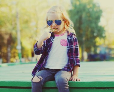 Portrait of stylish little girl child posing in a city park