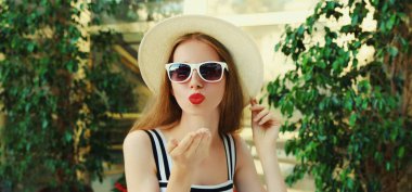 Güzel genç bir kadının portresi kırmızı dudaklar üflüyor kafede bir masada otururken tatlı bir öpücük yolluyor.